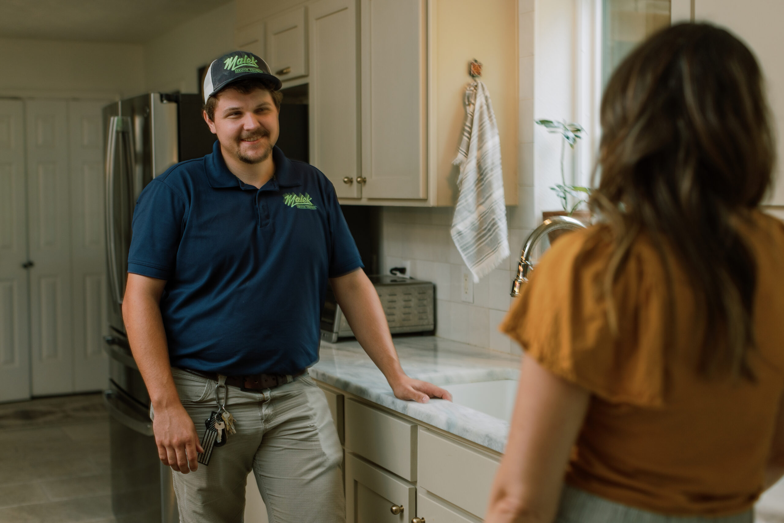Malek plumber inspecting tankless water heater components and connections