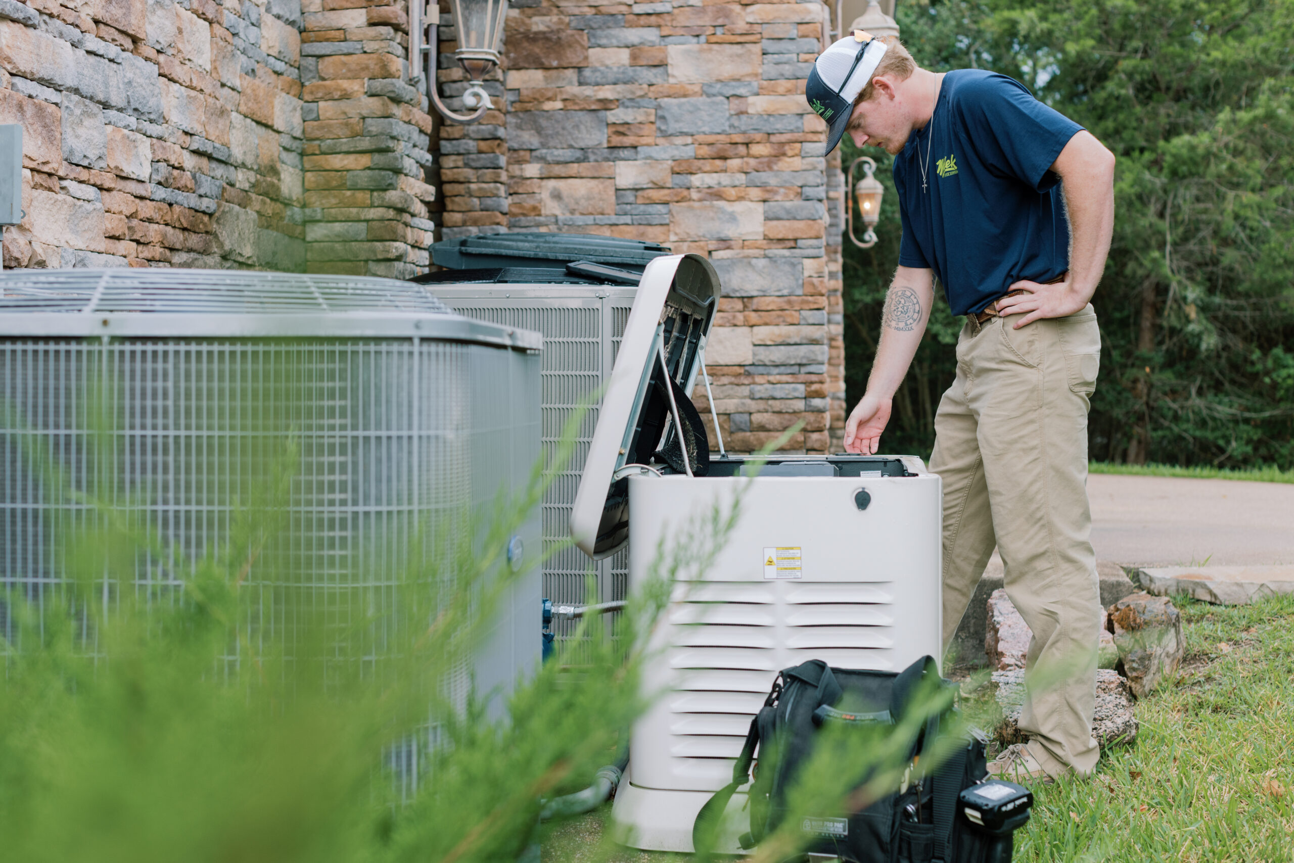 Malek technician performing maintenance on a residential whole-home standby generator